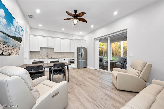 living room with ceiling fan, sink, and light hardwood / wood-style flooring