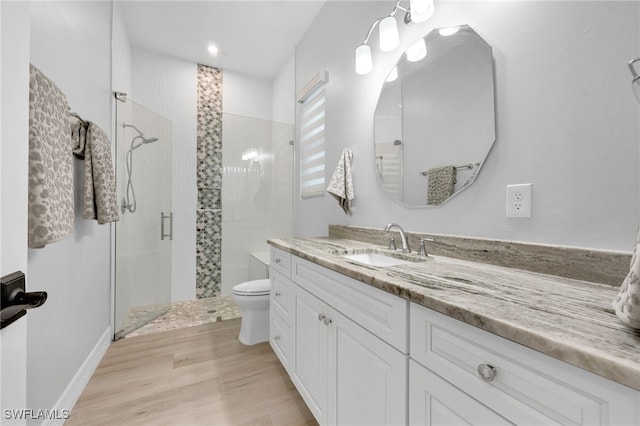 bathroom featuring a shower with door, vanity, wood-type flooring, and toilet