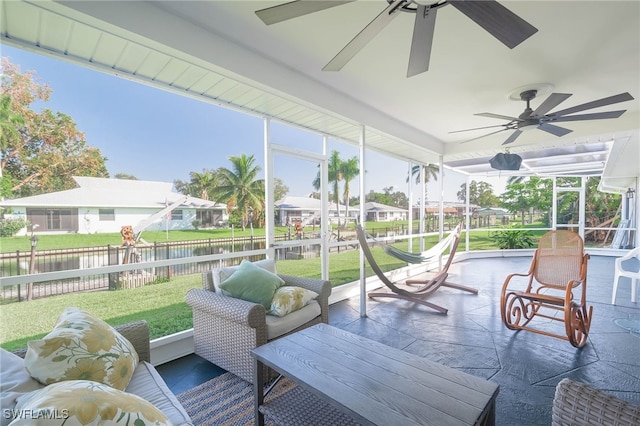 sunroom / solarium featuring a water view and ceiling fan