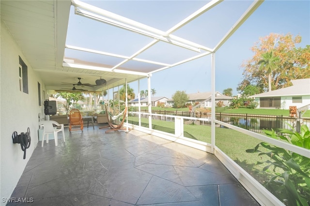 unfurnished sunroom with a water view and ceiling fan