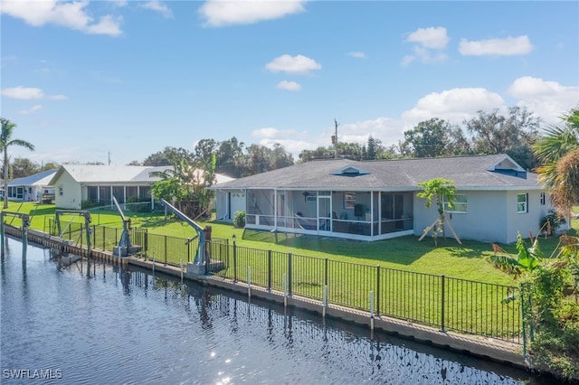 back of house with a sunroom, a lawn, and a water view