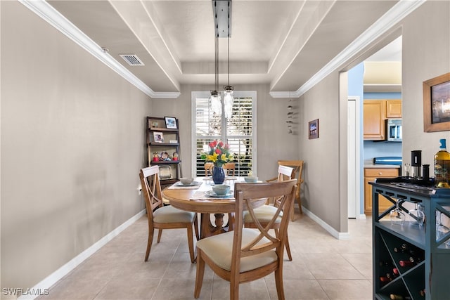 tiled dining space with ornamental molding and a raised ceiling