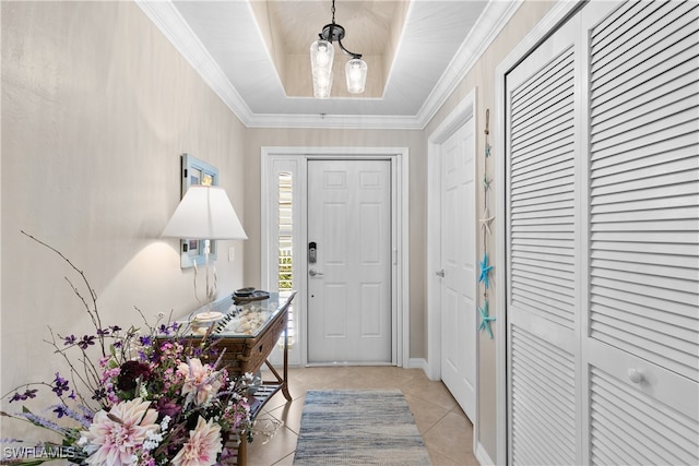 tiled foyer featuring crown molding, a tray ceiling, and a chandelier