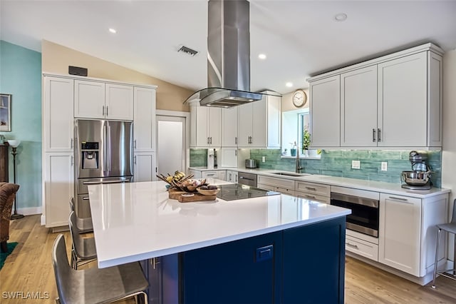 kitchen with island exhaust hood, a kitchen island, a breakfast bar, light hardwood / wood-style flooring, and stainless steel appliances