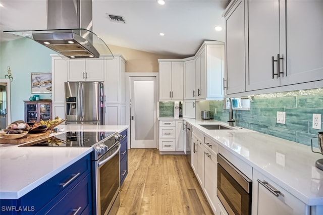 kitchen featuring appliances with stainless steel finishes, light hardwood / wood-style floors, lofted ceiling, white cabinets, and range hood