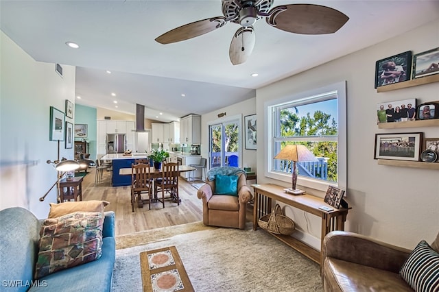 living room featuring light hardwood / wood-style floors, lofted ceiling, and ceiling fan