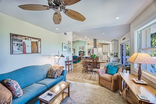 living room with ceiling fan, lofted ceiling, and light wood-type flooring