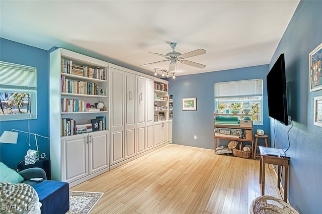 living area featuring light wood-type flooring and ceiling fan