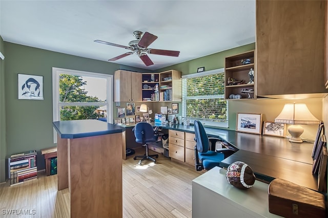 home office with built in desk, ceiling fan, and light wood-type flooring