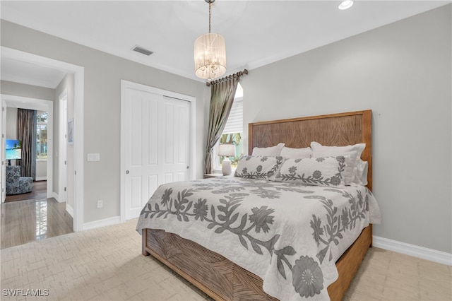 bedroom with an inviting chandelier, a closet, ornamental molding, and light wood-type flooring