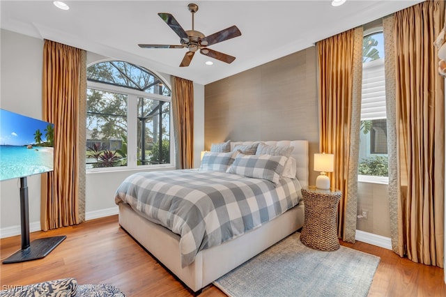 bedroom with ceiling fan, multiple windows, and light hardwood / wood-style floors