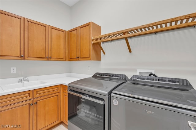 laundry room with sink, washing machine and clothes dryer, and cabinets