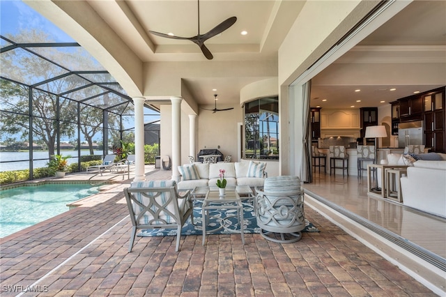 view of patio / terrace with a lanai, ceiling fan, a water view, an outdoor living space, and a bar