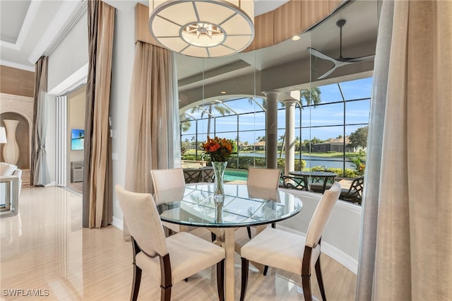 dining space featuring decorative columns, ceiling fan, a wall unit AC, a water view, and ornamental molding