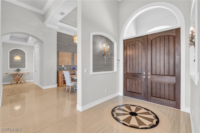 entryway with ornamental molding and light hardwood / wood-style flooring