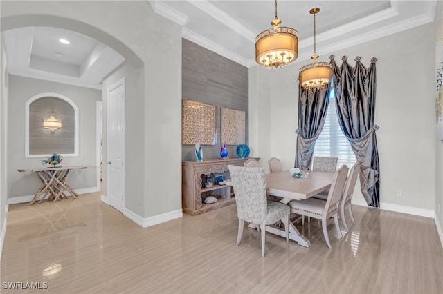 dining room featuring an inviting chandelier, ornamental molding, and a raised ceiling