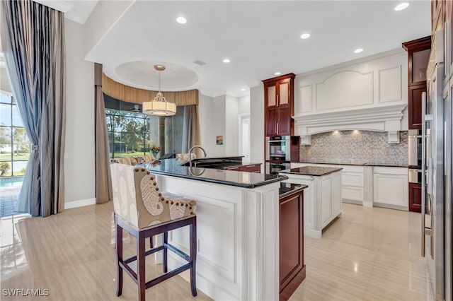 kitchen with backsplash, a center island with sink, sink, decorative light fixtures, and appliances with stainless steel finishes