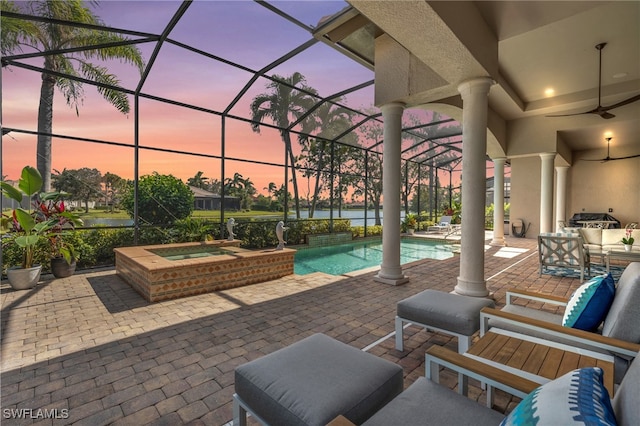 patio terrace at dusk featuring glass enclosure and a swimming pool with hot tub