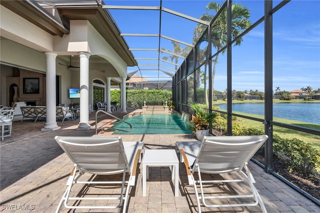 view of swimming pool featuring a water view, ceiling fan, glass enclosure, and a patio