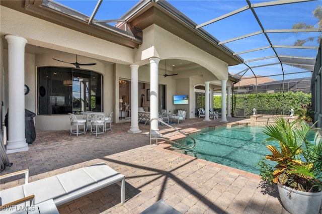 view of pool with a patio, ceiling fan, glass enclosure, and a hot tub