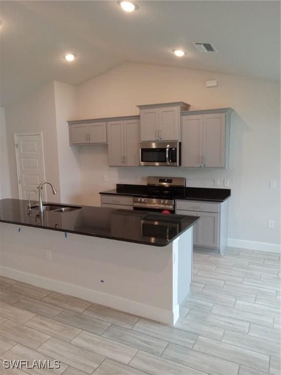 kitchen with gray cabinets, sink, appliances with stainless steel finishes, and vaulted ceiling