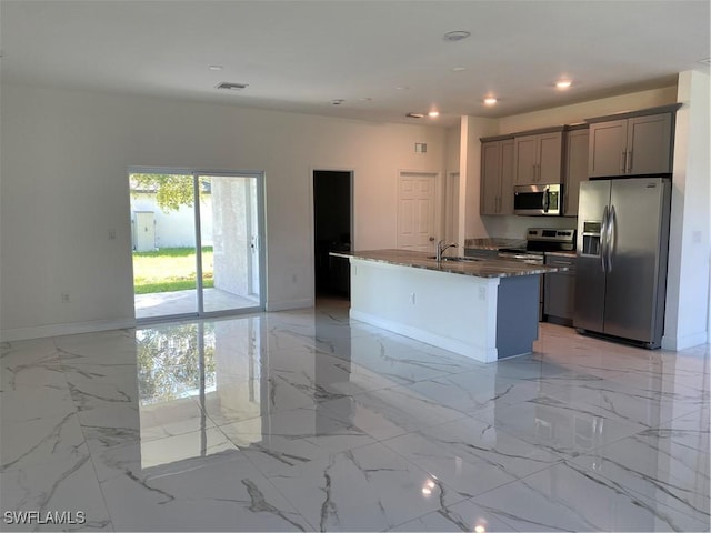 kitchen featuring sink, a center island with sink, gray cabinets, and appliances with stainless steel finishes