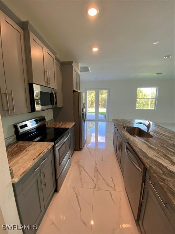 kitchen featuring french doors, sink, appliances with stainless steel finishes, gray cabinetry, and dark stone counters