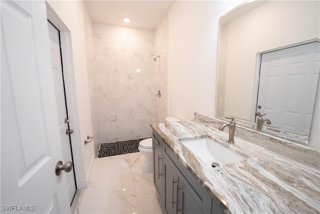 bathroom with tiled shower, vanity, and toilet