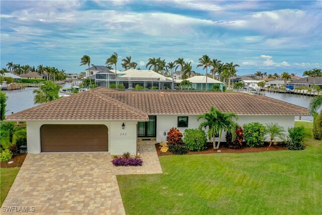 view of front of home with a lanai, a water view, a front yard, and a garage