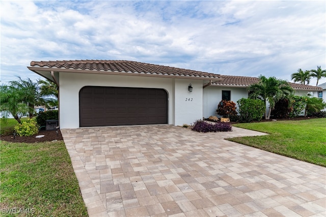 mediterranean / spanish-style home with a garage and a front lawn