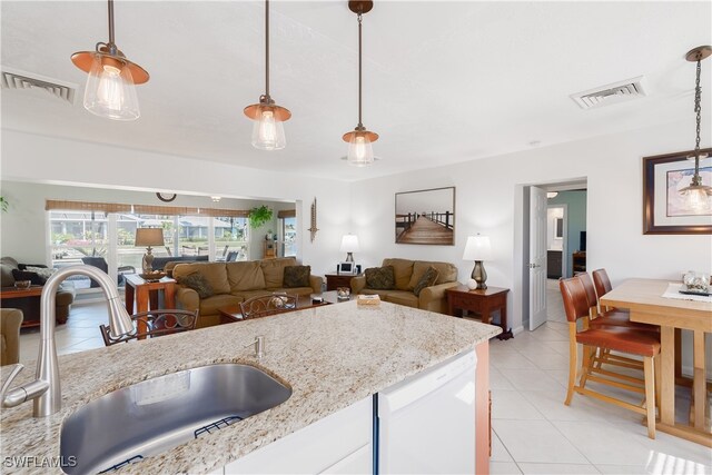 kitchen featuring light stone counters, sink, pendant lighting, light tile patterned floors, and white cabinetry