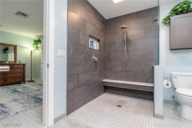 bathroom with tiled shower, tile patterned floors, vanity, and toilet