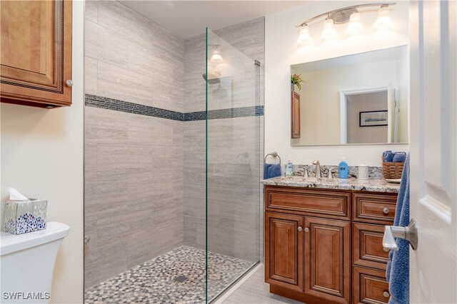 bathroom featuring a tile shower, vanity, and toilet