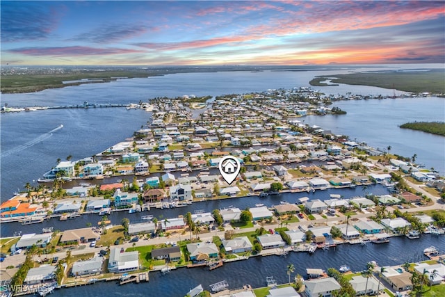 aerial view at dusk featuring a water view