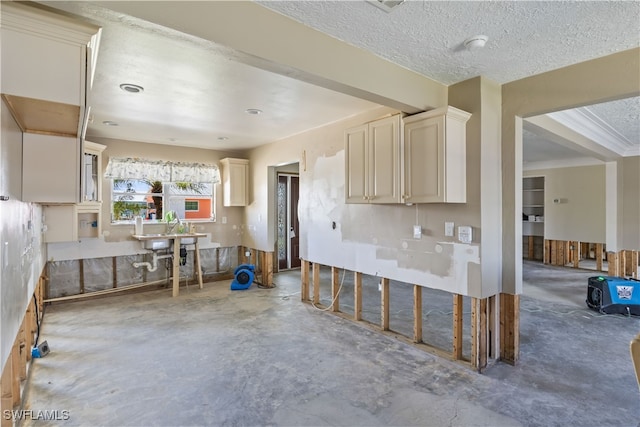 kitchen featuring a textured ceiling, concrete flooring, and cream cabinetry