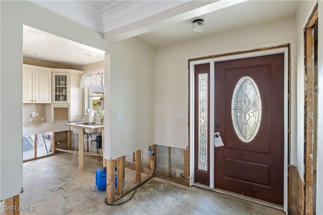 foyer with ornamental molding and concrete flooring