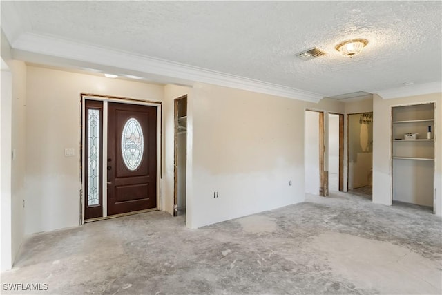 foyer entrance with ornamental molding and a textured ceiling