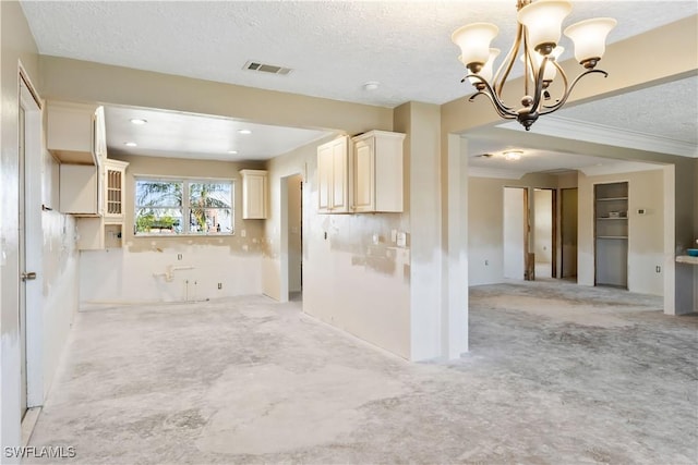 kitchen featuring a notable chandelier, decorative light fixtures, cream cabinetry, and a textured ceiling