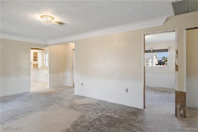 spare room featuring ornamental molding, concrete floors, and a textured ceiling