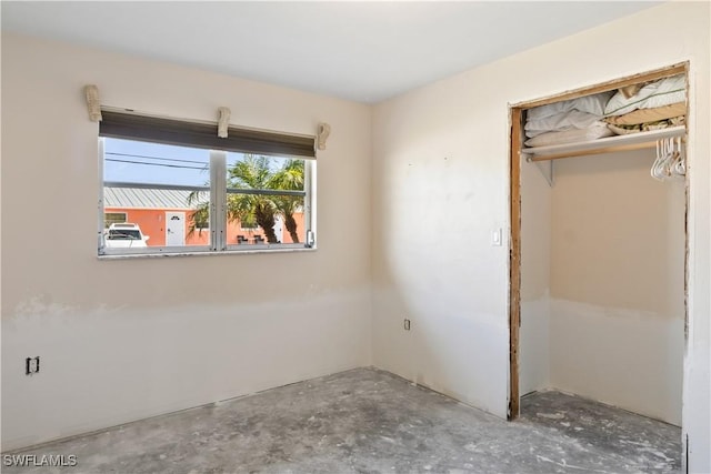 unfurnished bedroom featuring concrete floors and a closet