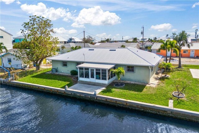 rear view of property with a water view, a patio, a sunroom, and a lawn