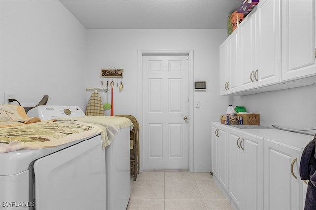 clothes washing area with a textured ceiling, washer and clothes dryer, light tile patterned flooring, and cabinets