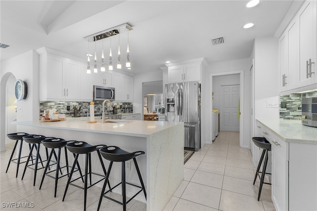 kitchen with white cabinetry, stainless steel appliances, a breakfast bar, and hanging light fixtures