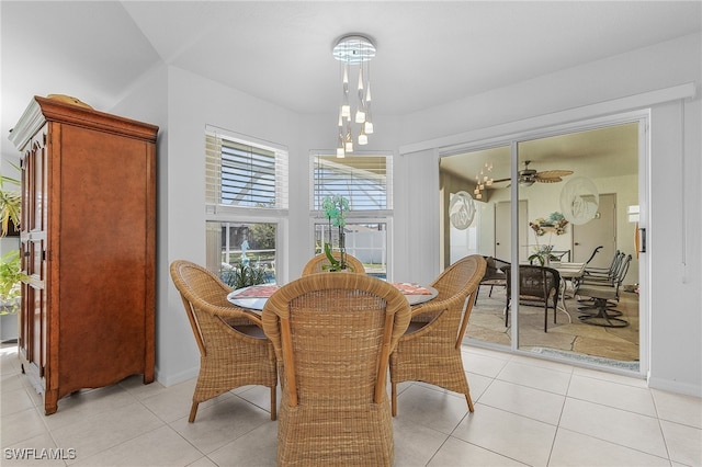 tiled dining space with ceiling fan with notable chandelier