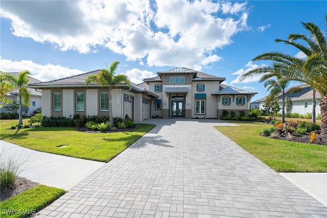 view of front of house featuring stucco siding, french doors, decorative driveway, and a front yard