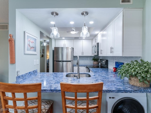 kitchen with kitchen peninsula, white cabinets, a breakfast bar area, backsplash, and stainless steel appliances