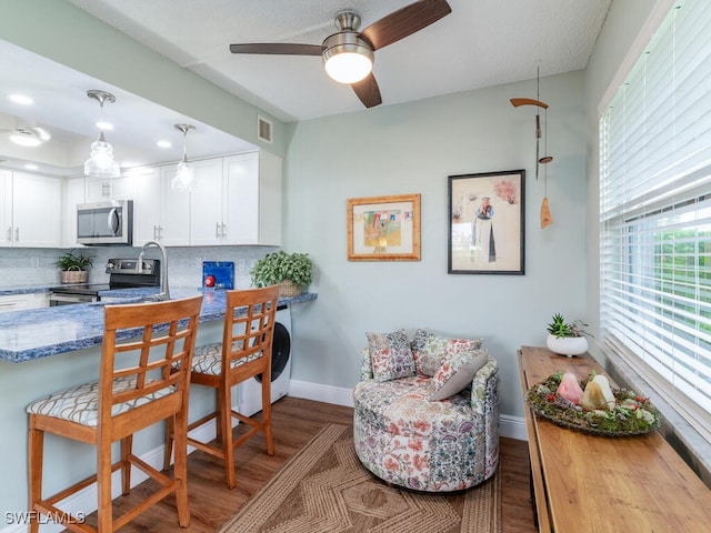 kitchen featuring decorative backsplash, white cabinetry, stainless steel appliances, and hardwood / wood-style flooring