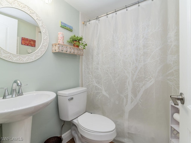 bathroom featuring toilet, walk in shower, and sink