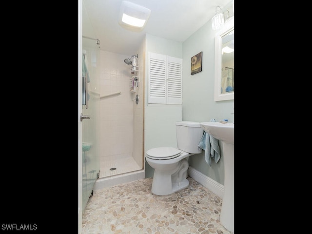 bathroom with tile patterned floors, a shower with shower door, and toilet