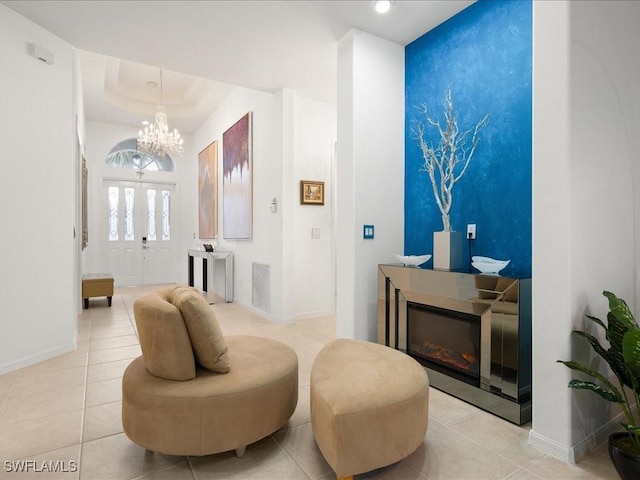 sitting room featuring a chandelier, light tile patterned floors, and a raised ceiling